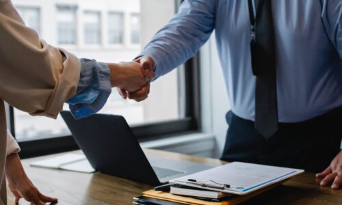 crop colleagues shaking hands in office