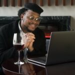 man in black jacket sitting in front of a laptop computer