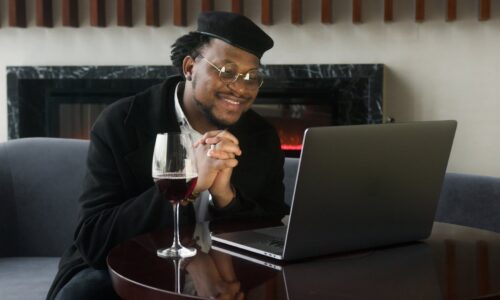 man in black jacket sitting in front of a laptop computer